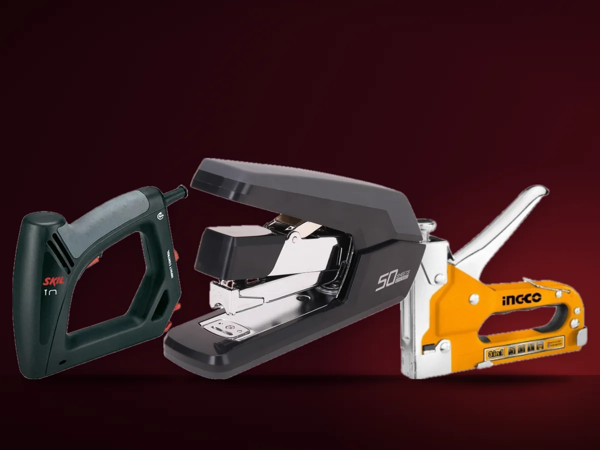 Un capsator de birou metalic, un capsator manual de tapiterie si unul electric, pe un banc de lucru